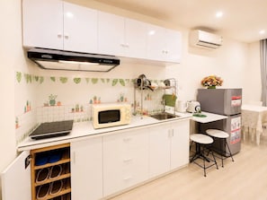Uma cozinha compacta com armários brancos, micro-ondas, pia e geladeira.