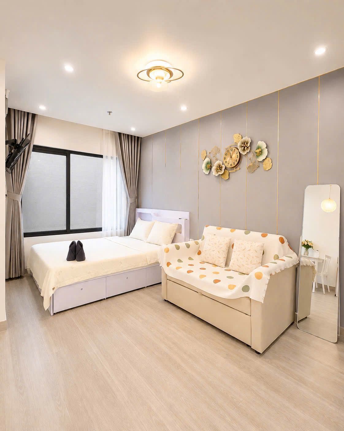 Un dormitorio moderno con cama, sofá, espejo y un reloj de pared.