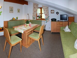 Una habitación acogedora con una mesa de comedor, sillas, un sofá, un televisor y un armario.
