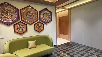 A lobby with a green sofa, patterned wall decorations, and a checkered floor.