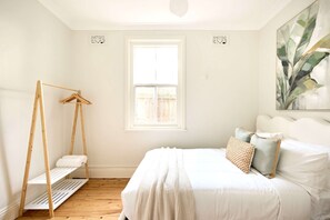 Une chambre avec un lit, une balançoire en bois, une fenêtre et un tableau.