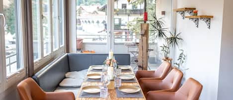 A dining area with a wooden table set for six, surrounded by leather chairs, with a view of the outside.