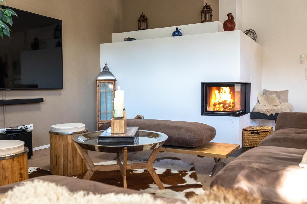 Una sala de estar con chimenea, un televisor montado en la pared y un rincón de descanso acogedor con cojines.