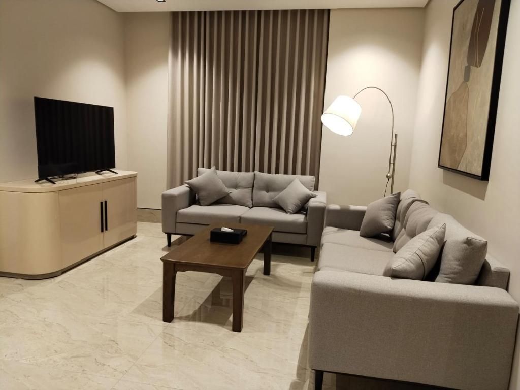 A modern living room with a sofa set, a coffee table, a TV, and a floor lamp.