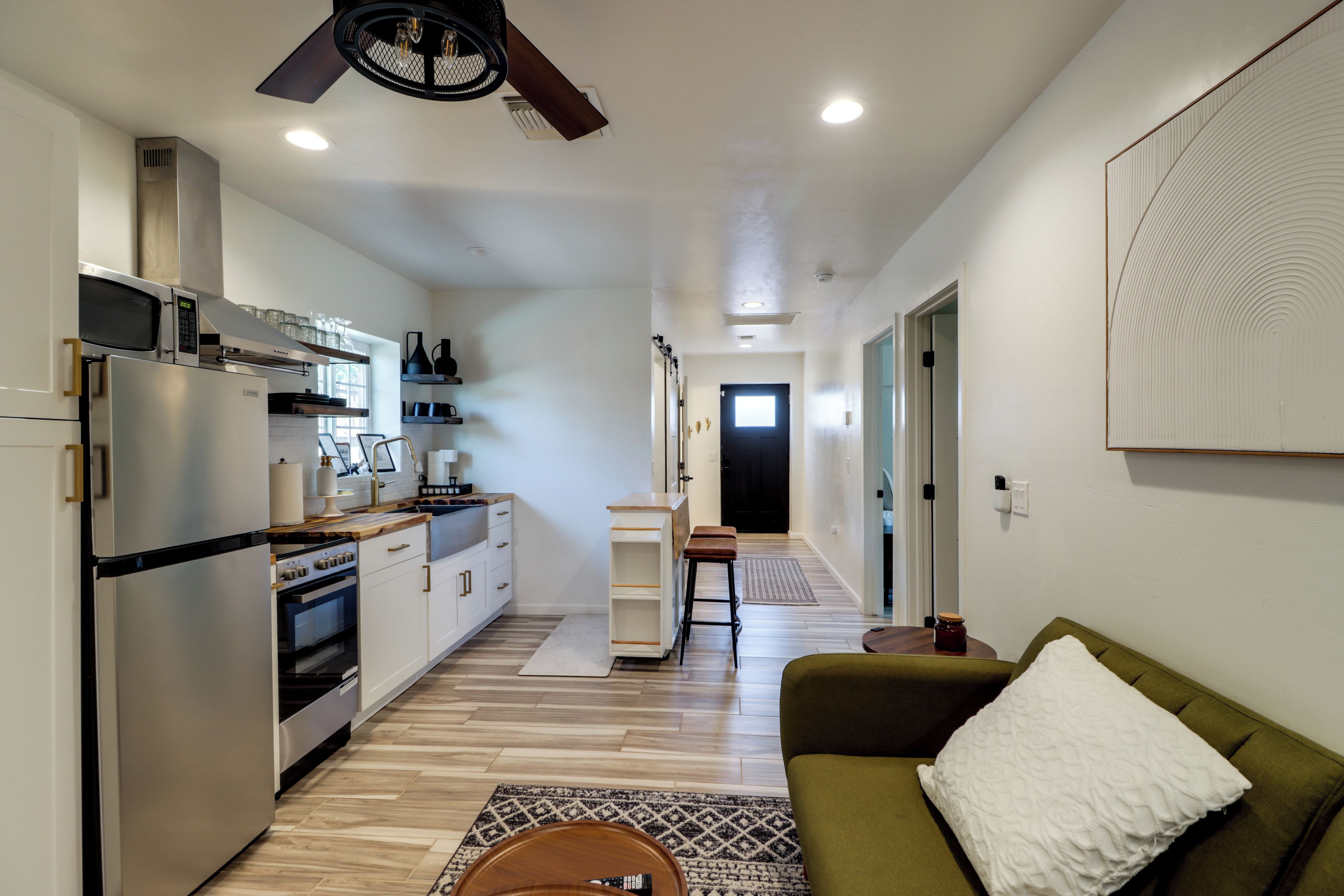 Una cocina moderna con electrodomésticos de acero inoxidable, encimera de madera y ventilador de techo negro.