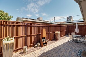 Eine Terrasse mit Holzzaun, Gartenmöbeln und einem Tisch mit Stühlen.