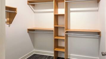 A closet with open shelves and a central hanging rod.