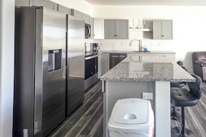 A modern kitchen with stainless steel appliances, a granite countertop, and a built-in dishwasher.