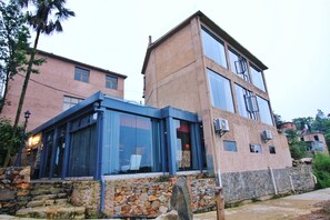 A two-story building with a stone facade, large windows, and a glass-enclosed area with a stone base.