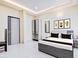 A modern hotel room with a large bed, a wardrobe, a bedside table, and a mirror. - Classic Joka Industrial Plaza (Alipur)