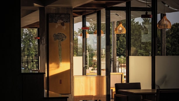 A modern interior with large windows, wooden furniture, and hanging pendant lights. - THE HAN HOTEL (Kathmandu)