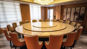 A conference room with a large oval table surrounded by chairs, wooden paneling on the walls, and artwork on the upper right. - THE HAN HOTEL (Kathmandu)