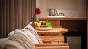 A dining area with a wooden table, a bowl of fruit, and a vase with a flower. - THE HAN HOTEL (Kathmandu)