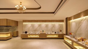 En moderne hotellobby med en reception i marmor, en lysekrone og et buffetområde.