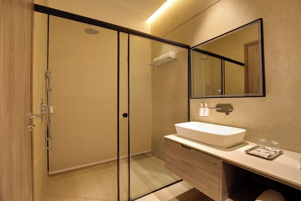 A modern bathroom with a glass-enclosed shower, a wooden vanity, and a large mirror.