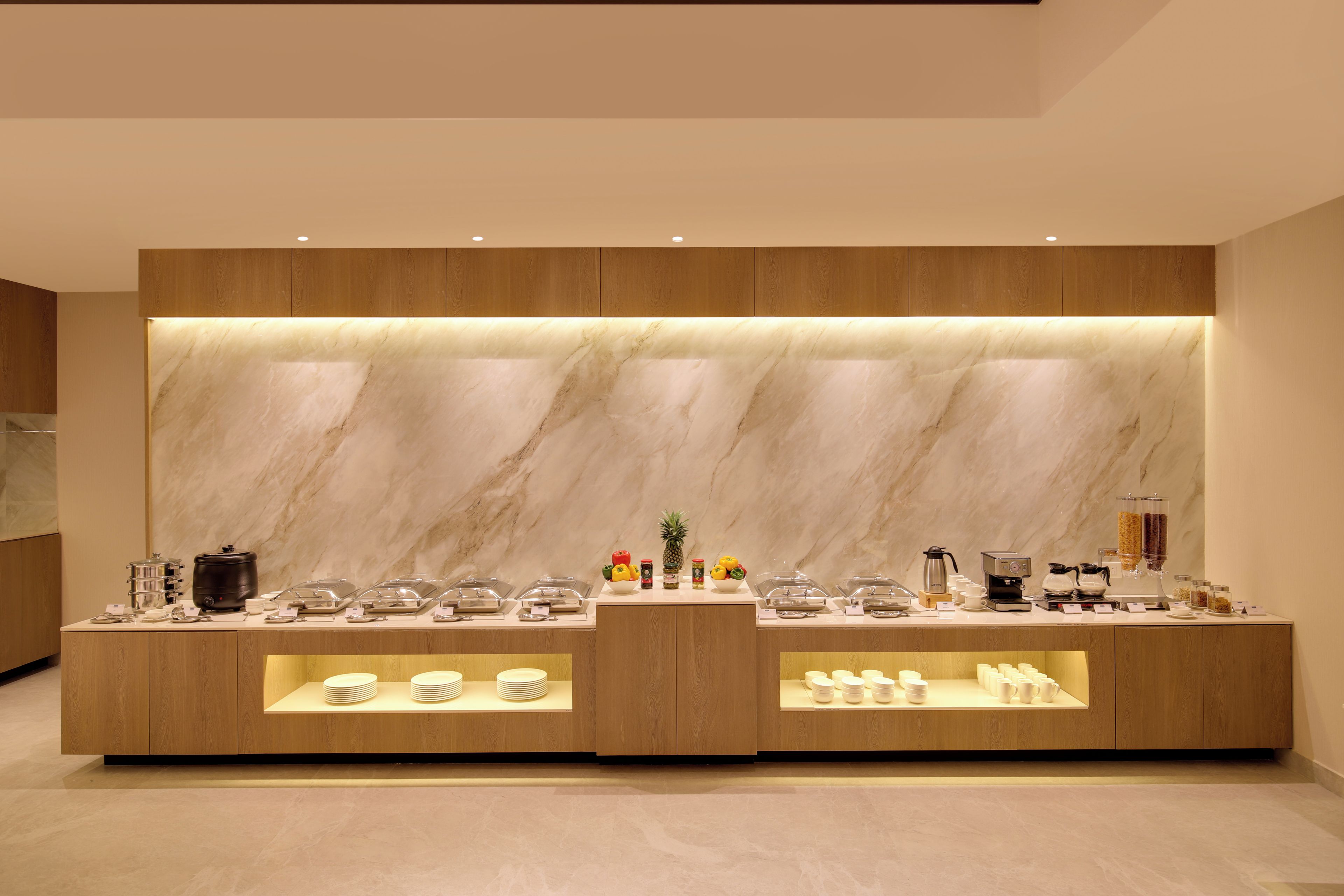 A modern buffet setup with marble backdrops and a coffee station.