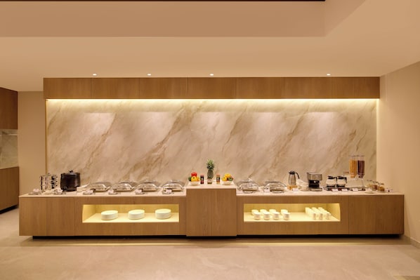 A modern buffet setup with marble backdrops and a coffee station.