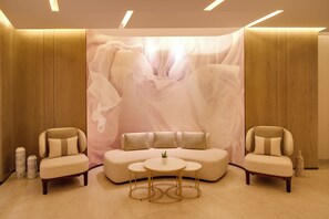 Un interior moderno con un sofá, dos sillones, una mesita redonda y un elemento decorativo de fondo.