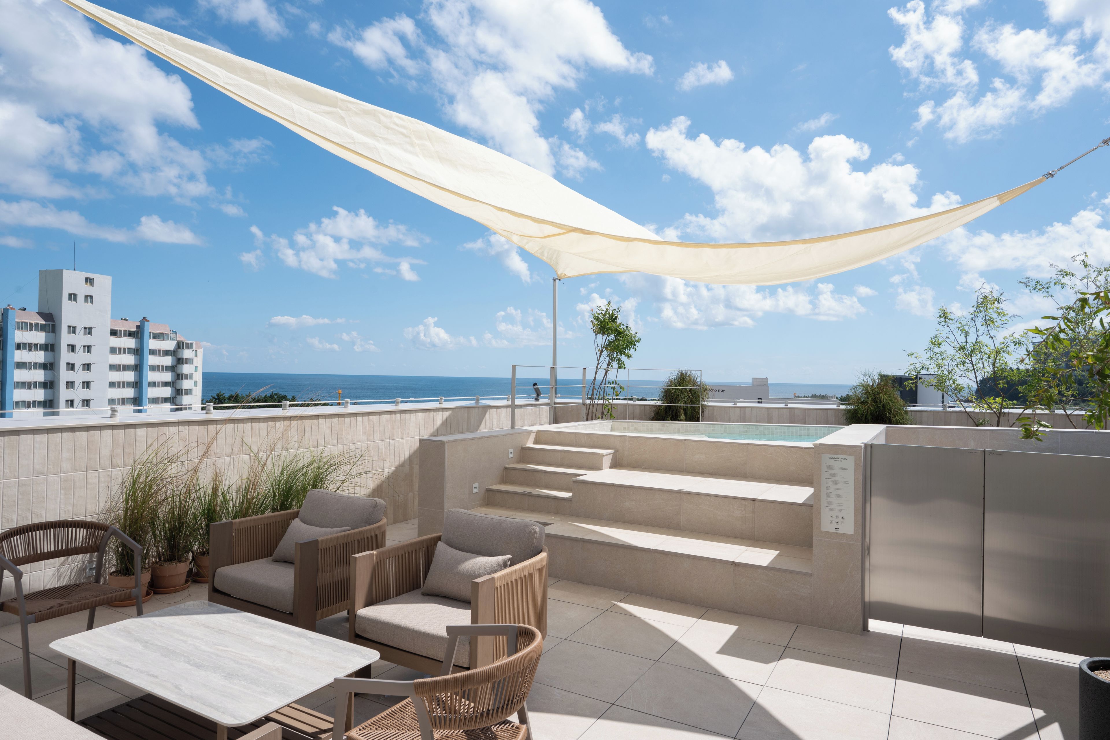 A rooftop terrace with outdoor seating, a pool, and a view of the sea.
