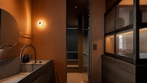 Un baño moderno con un espejo curvo, un lavabo y una lámpara de pared.