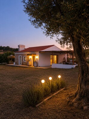 Una casa moderna amb teulada de rajola vermella, un porxo cobert i il·luminació exterior.