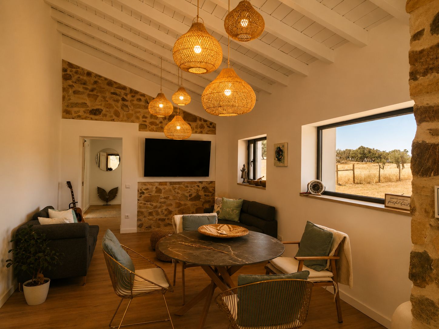 A cozy living room with a stone wall, a round table, and wicker chairs.