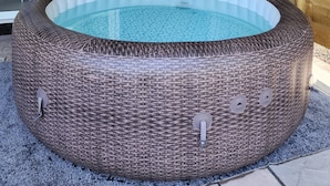 Un jacuzzi con revestimiento de mimbre, puerta de cristal y techo de madera.