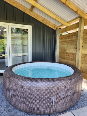 A hot tub with a wicker exterior, a glass door, and a wooden ceiling. - The PigSty at the Secret Garden (Biddenden)