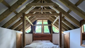 Un dormitorio con techo de madera, una cama grande y una ventana.