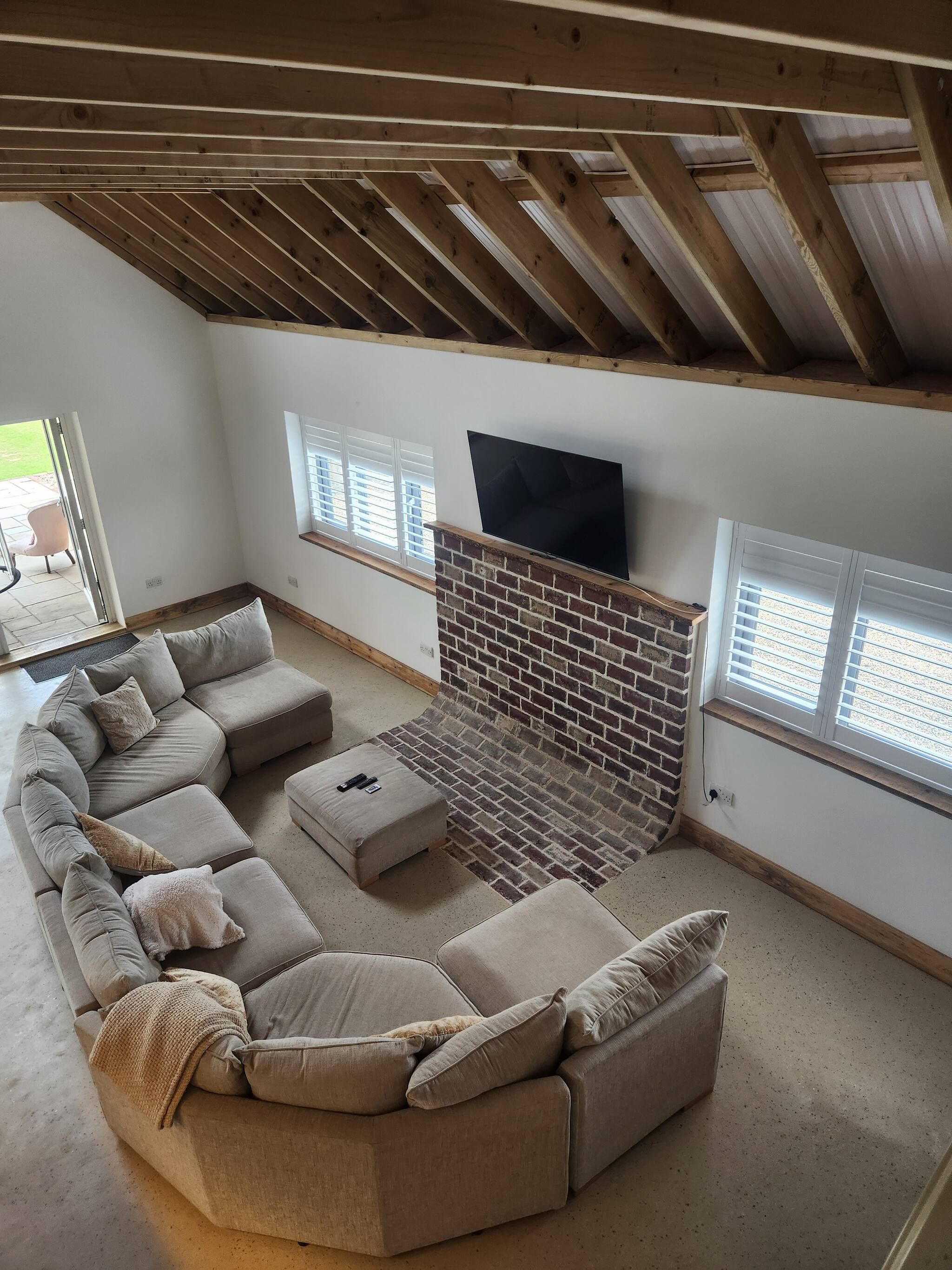 A living room with a sectional sofa, a fireplace, and a TV mounted on the wall.