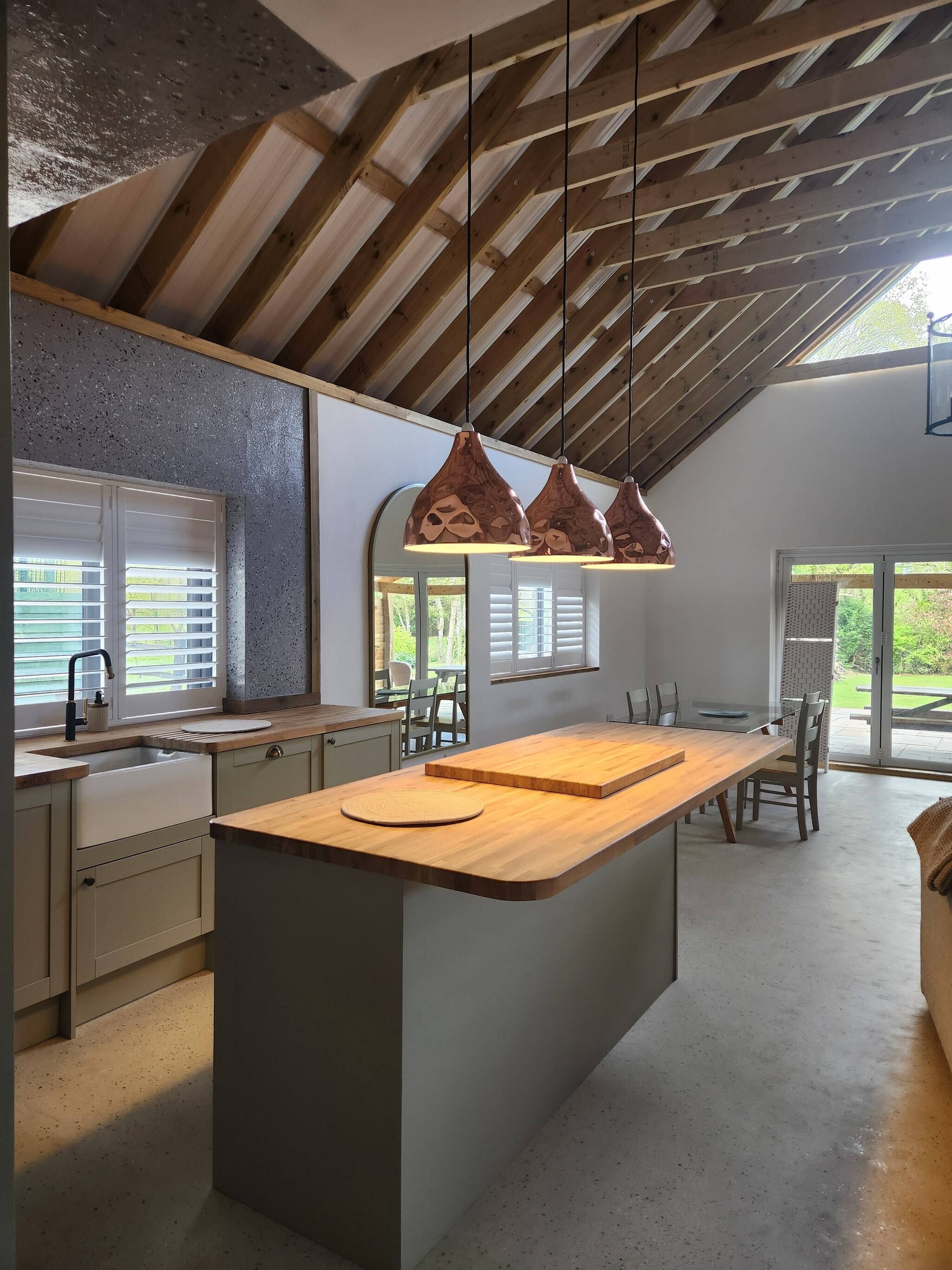 A modern kitchen with a central island, pendant lights, and a view of the outdoors.