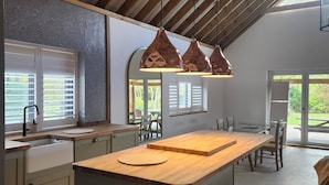 Una cocina moderna con una isla central, luces colgantes y vistas al exterior.