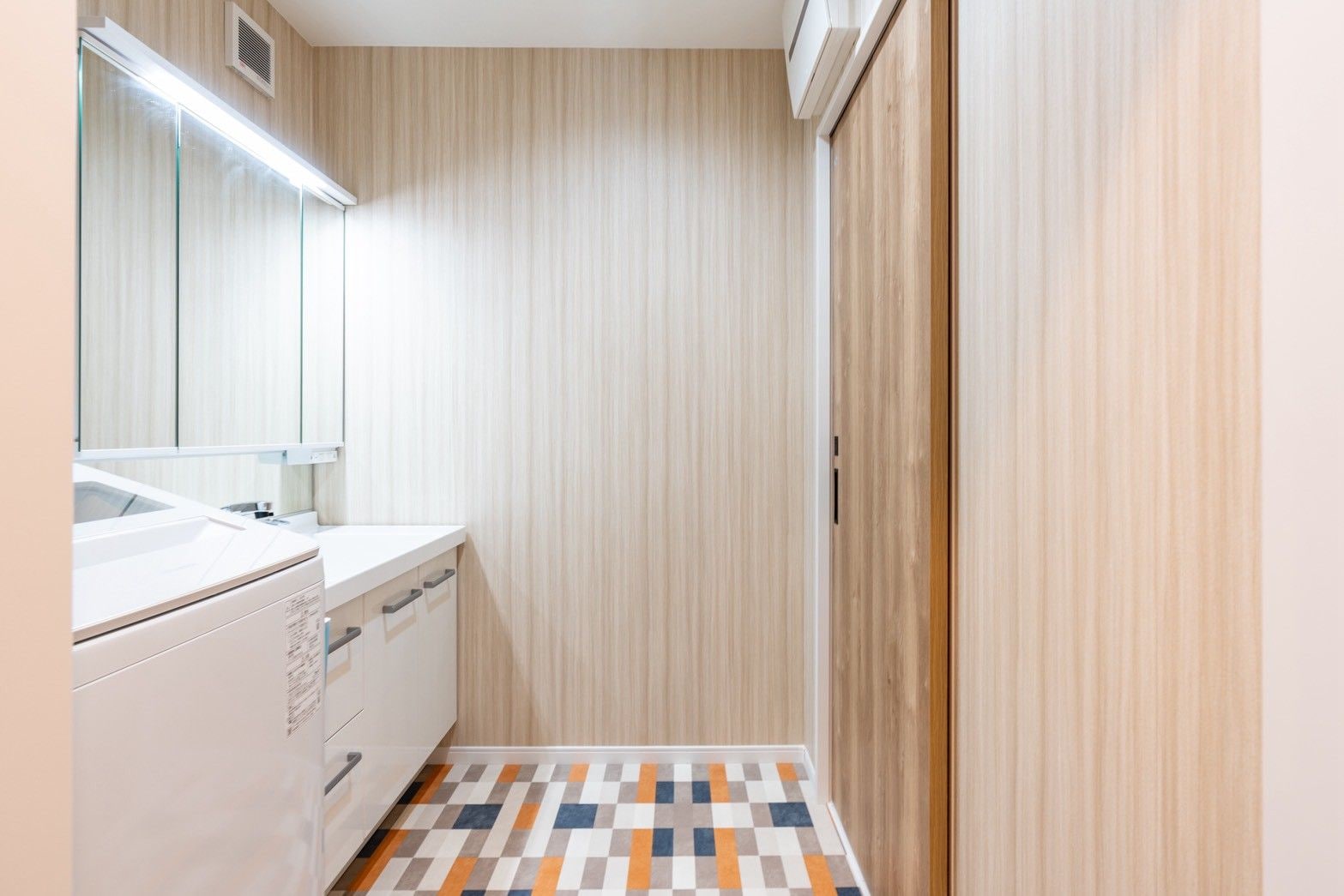 A bathroom with a white sink, mirror, and a patterned floor.
