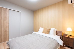 Ein Schlafzimmer mit einem Bett, einem Nachttisch, einer Lampe und einem Kleiderschrank.
