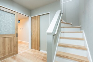 Ein modernes Interieur mit Holzboden, einer Treppe mit weißen Geländern und einer Tür mit Milchglasfenster.