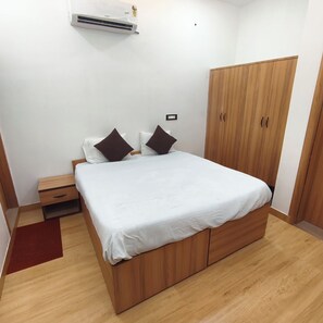 Un dormitorio con una cama de madera, una mesita de noche, un armario y un equipo de aire acondicionado.