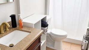 Un baño con lavamanos, inodoro y cortina de ducha.