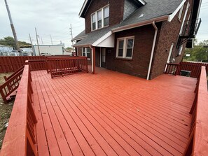 A red wooden deck with a brick house in the background.