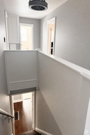A staircase with a white handrail, a wooden door at the bottom, and a ceiling fan.