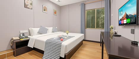 Habitación de hotel con cama, mesita de noche, televisión y ventana con cortinas.