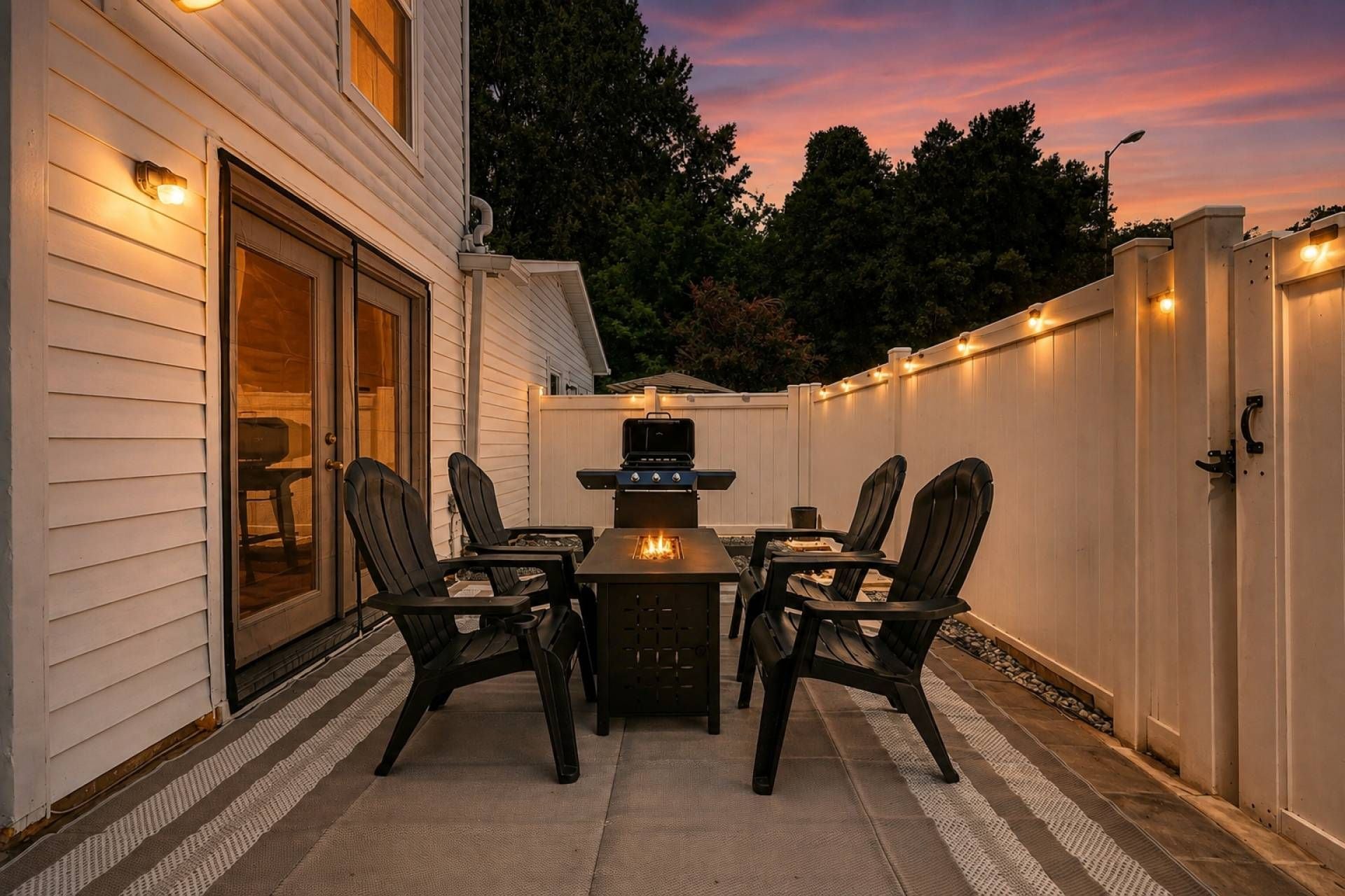 Eine Terrassengruppe im Freien mit Grill, vier Stühlen und einem Tisch.