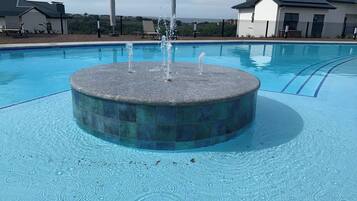 Una piscina con una fuente central y una zona de solárium alrededor.