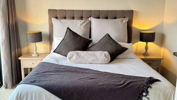 A neatly made bed with a dark and light patterned bedspread, two pillows, and a decorative throw.