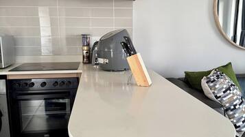 A modern kitchen with a built-in oven, a coffee maker, and a knife block on the countertop.