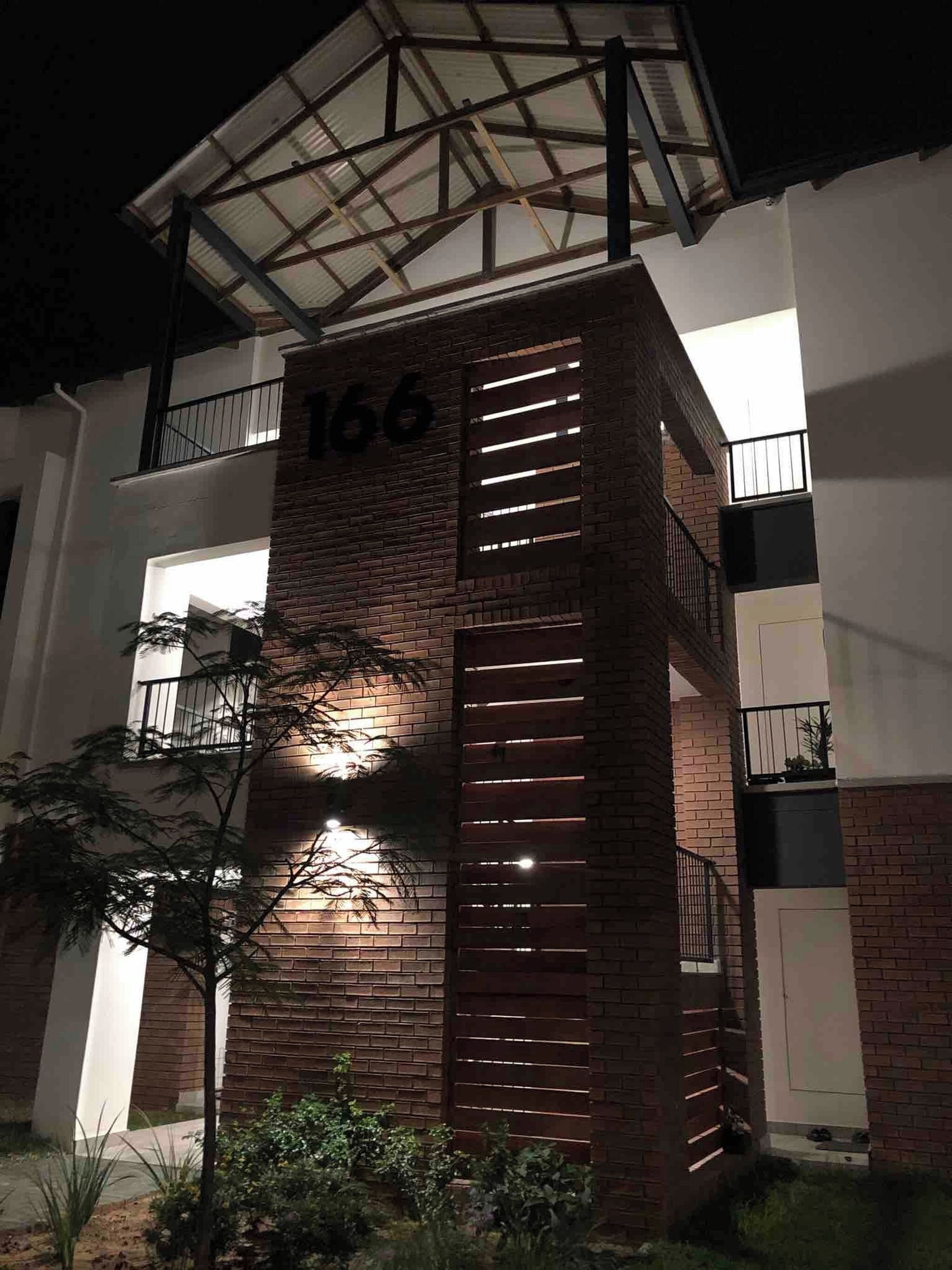 A building with a brick facade, a balcony with metal railings, and the number '166' on the side.