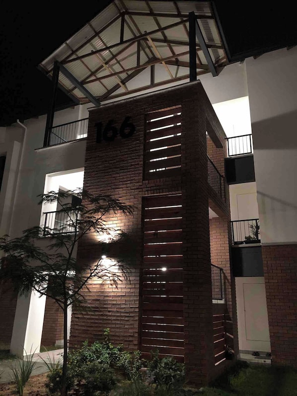 A building with a brick facade, a balcony with metal railings, and the number '166' on the side.