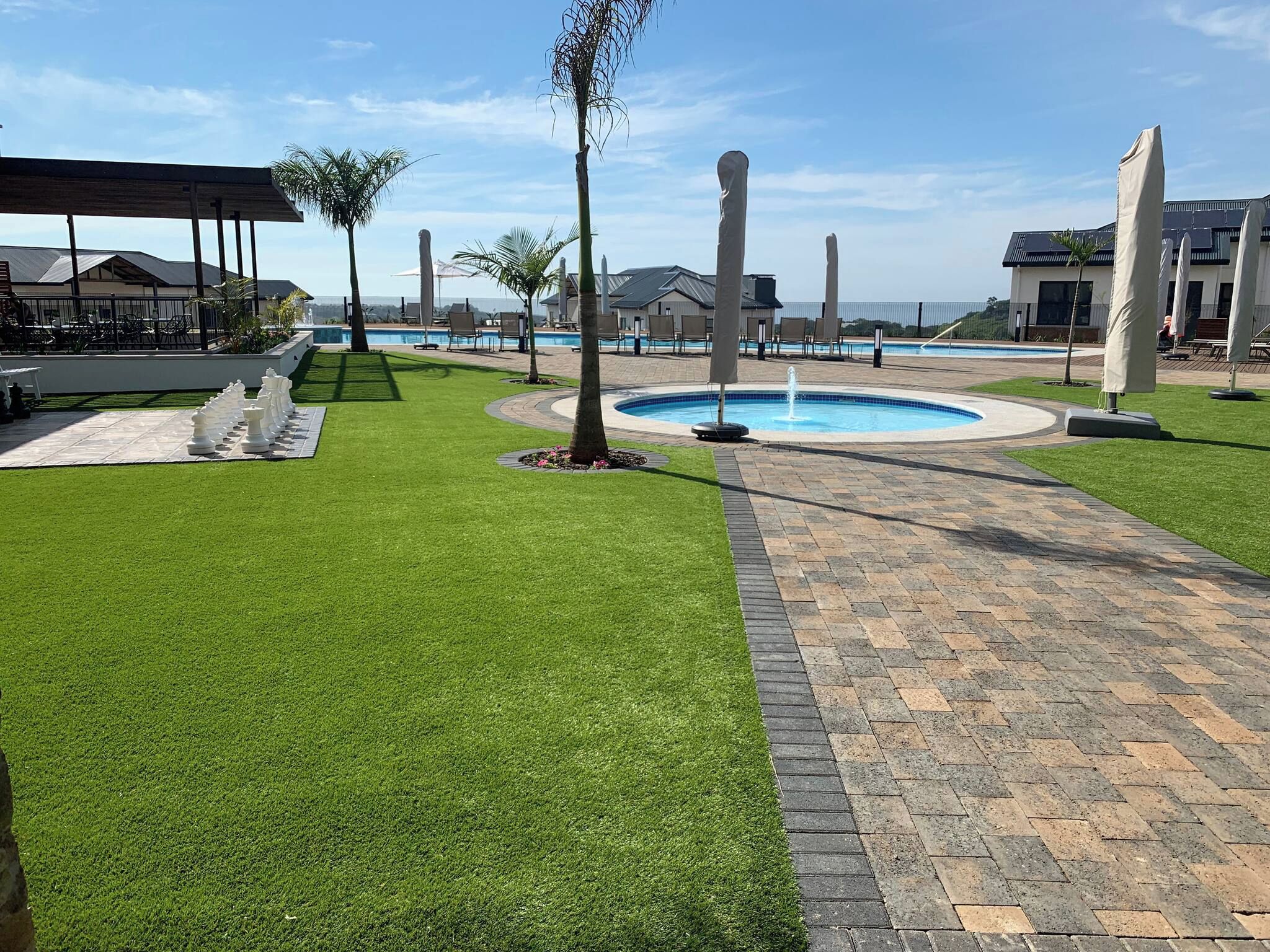 A landscaped outdoor area with a pool, seating, and a chessboard.