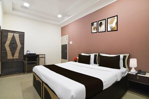 A hotel room with a bed, bedside table, nightstand, wardrobe, and artwork on the wall. - Classic rm Guest Home (Kolkata)