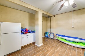 Una habitación con refrigerador, armarios, ventilador de techo y un kayak.