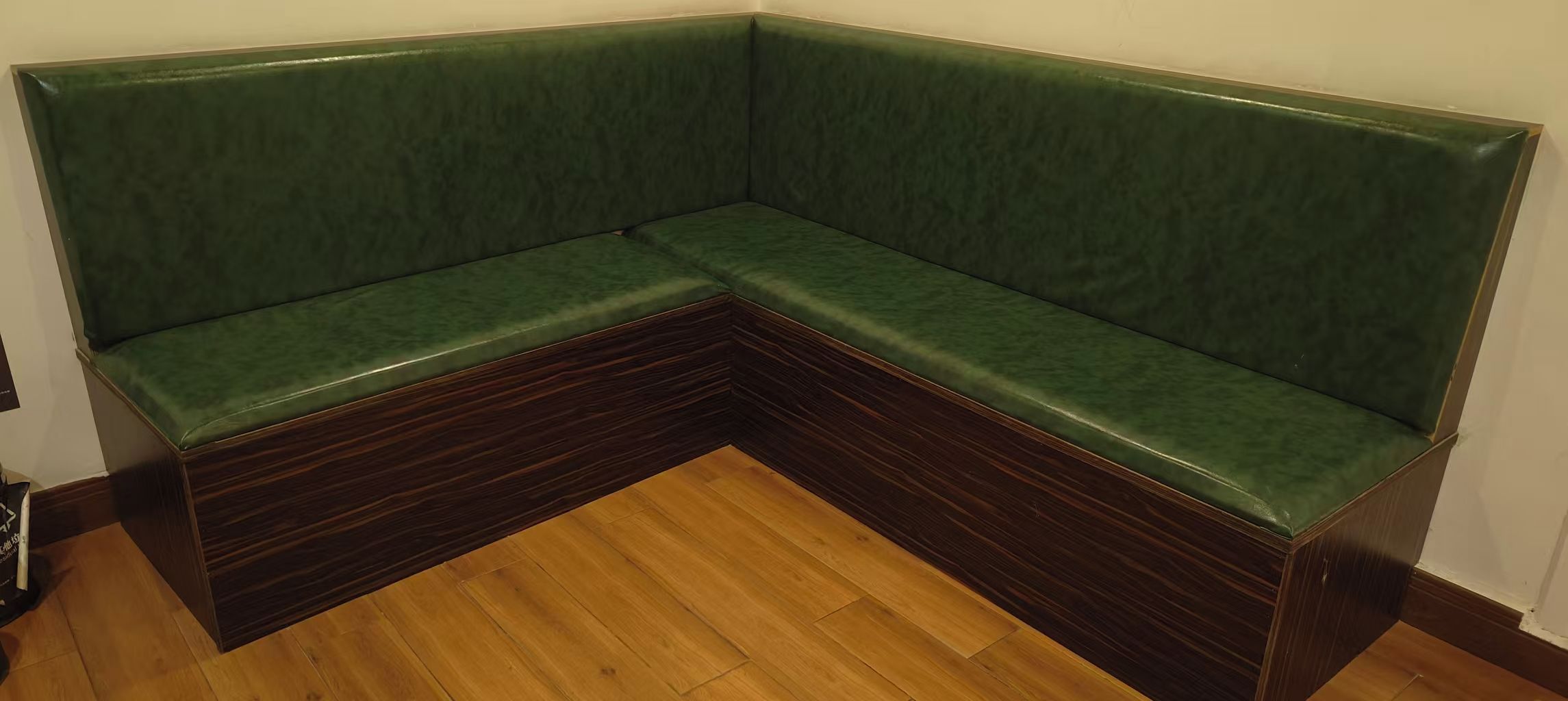 A corner sofa with a dark wood base and green upholstery.